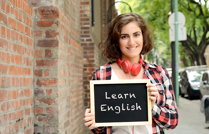 woman holding a learn english sign