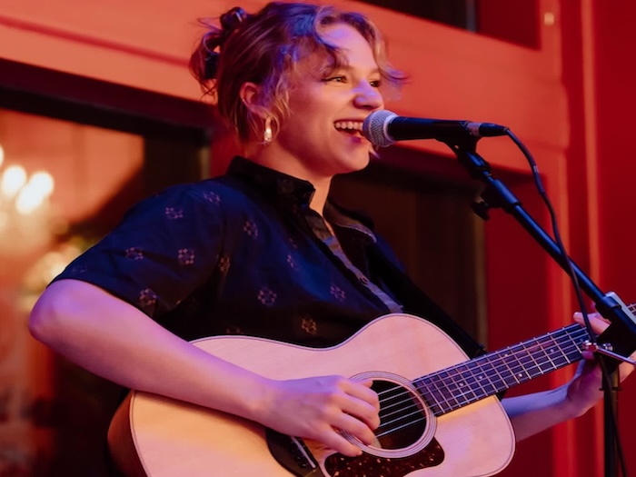 Hannah singing with a guitar