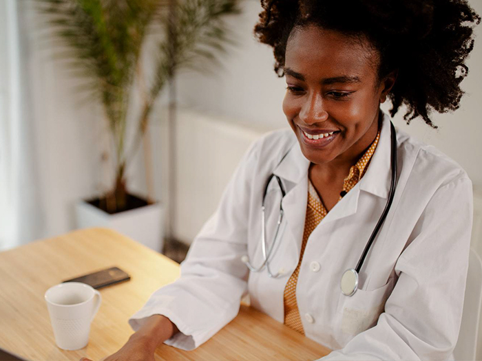 woman in lab coat using laptop