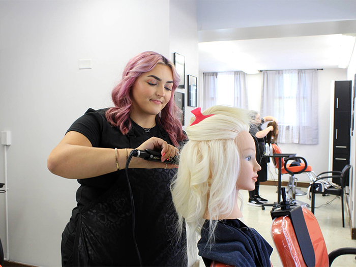 student curling hair on a mannequin